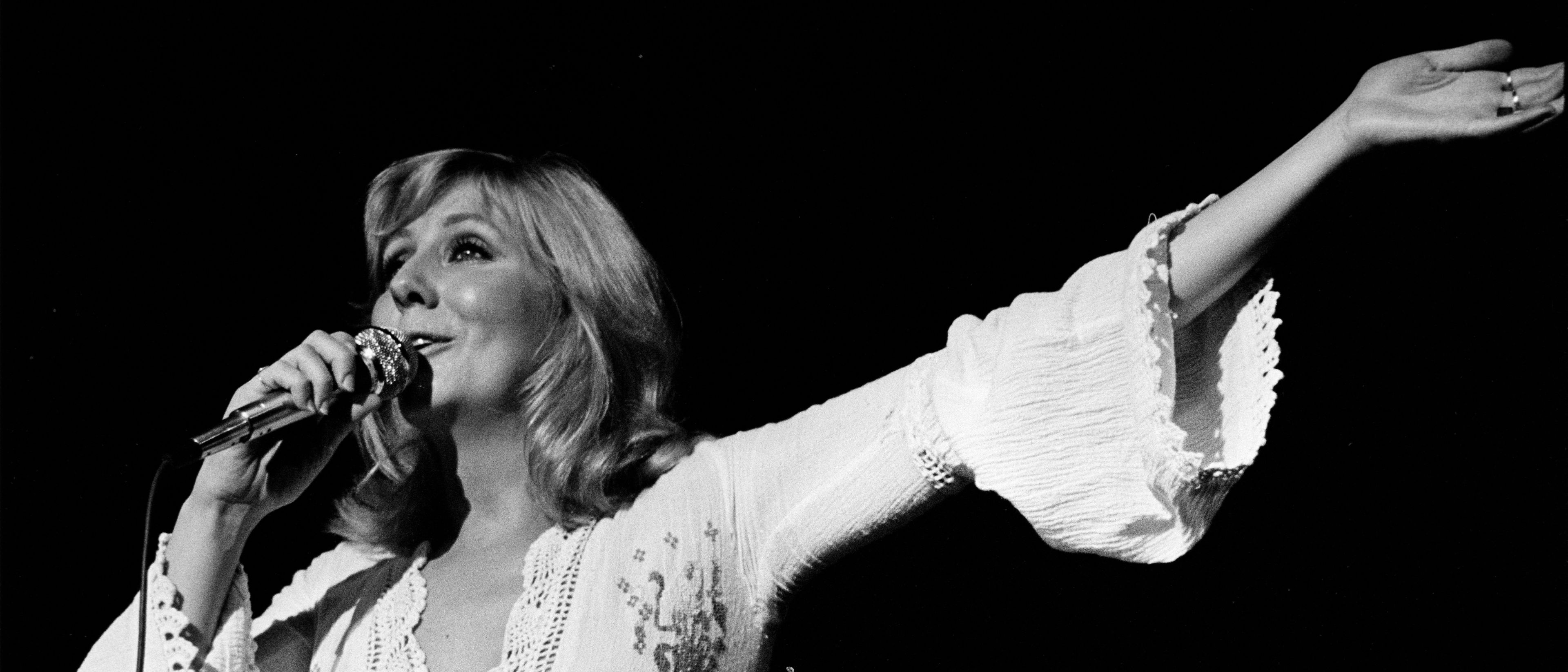 Photo en noir et blanc de Renée Martel chantant sur scène