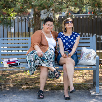 Deux femmes assises sur un banc de parc avec une pile de livres.