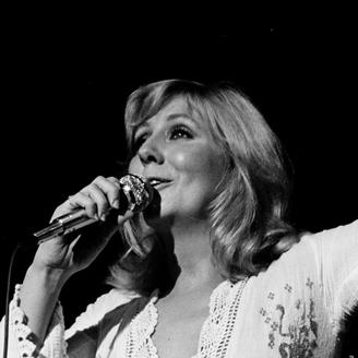 Photo en noir et blanc de Renée Martel chantant sur scène